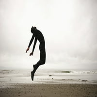 Pojedinac koji nosi mokro odijelo koje skače u sredinu zraka na plaži; Francuska plaža, britanska Kolumbija,